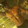 Still image from the short film In a Strange Room. A shirtless, oiled and very muscular man is dancing in a club. 