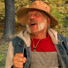 Still image from short film, Pops' Corn showing a smiling man with a grey beard and a fishing hat with trees in the background.