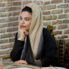 Still image from the documentary Red Liptick, showing Masoumeh wearing a headscarf resting her shin on her hand, with bright red lipstick on her lips.. 